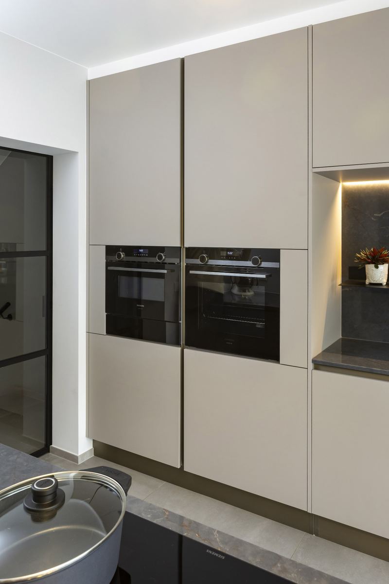 Tall Zecchinon units in warm grey with built-in ovens and a lit niche